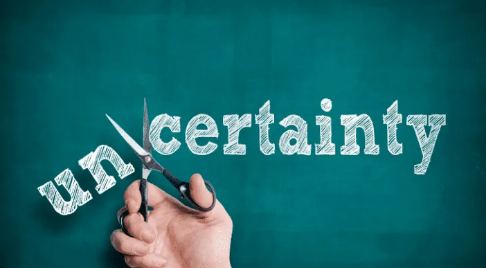 Een hand knipt het woord uncertainty door en maakt een einde aan onzekerheid